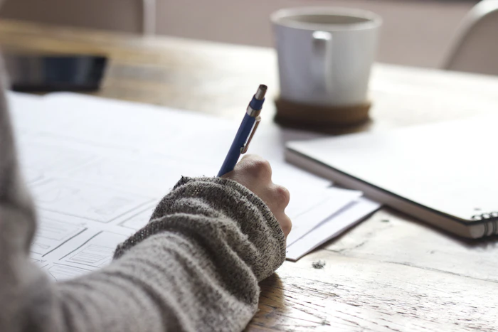 Student studying at a wooden desk with an open notebook and warm lamp light