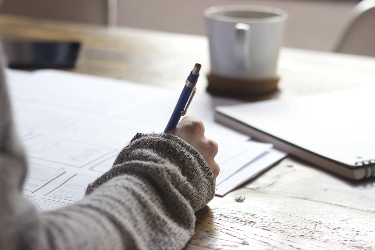 Student studying at a wooden desk with an open notebook and warm lamp light
